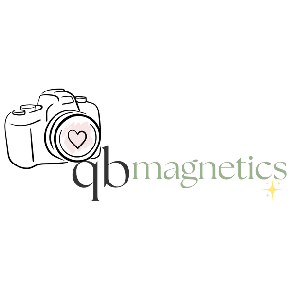QB Magnetics transparent logo with a minimalist black camera outline, soft pink heart lens, and elegant ‘qb magnetics’ typography with star sparkles — representing custom photo magnets, personalized Polaroid-style magnets, fridge photo keepsakes, and high-quality magnetic décor.
