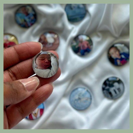 Hand holding a custom glass cabochon photo magnet featuring a newborn baby — personalized round fridge magnet with domed glass finish, perfect for memory keeping, baby announcements, or sentimental gifts